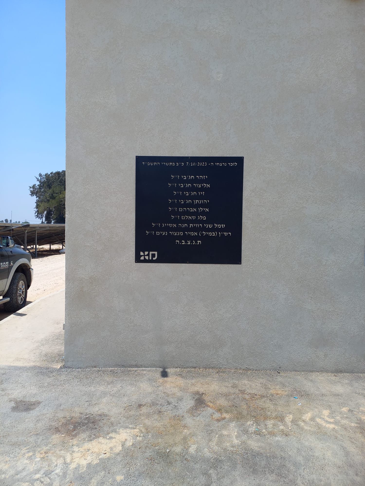 שלט הנצחה שחור ממתכת עם שמות הנופלים על קיר מבנה
