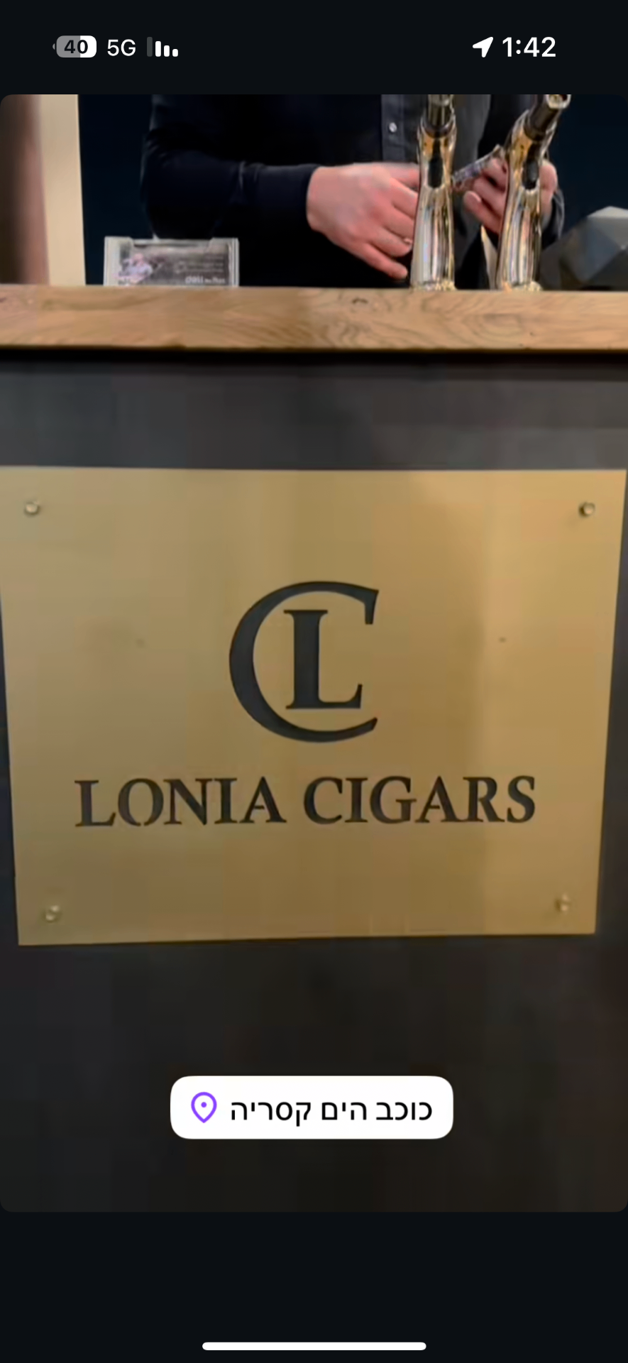 שלט מתכת זהוב „LONIA CIGARS” עם לוגו CL על דלפק