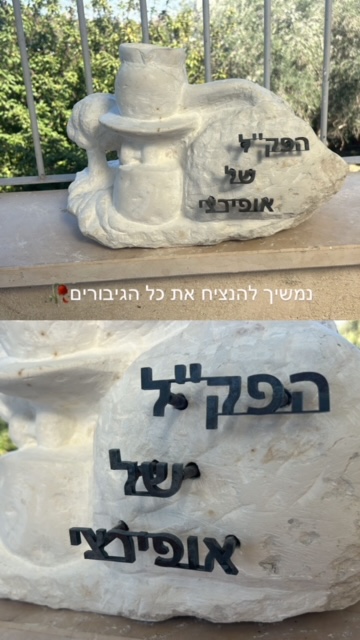 אותיות מתכת שחורות בכיתוב הנצחה על פסל אבן לבן