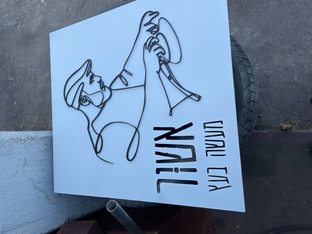 שלט מתכת לבן „אשור מעשה בעץ” עם איור קו שחור של נגר בעבודה