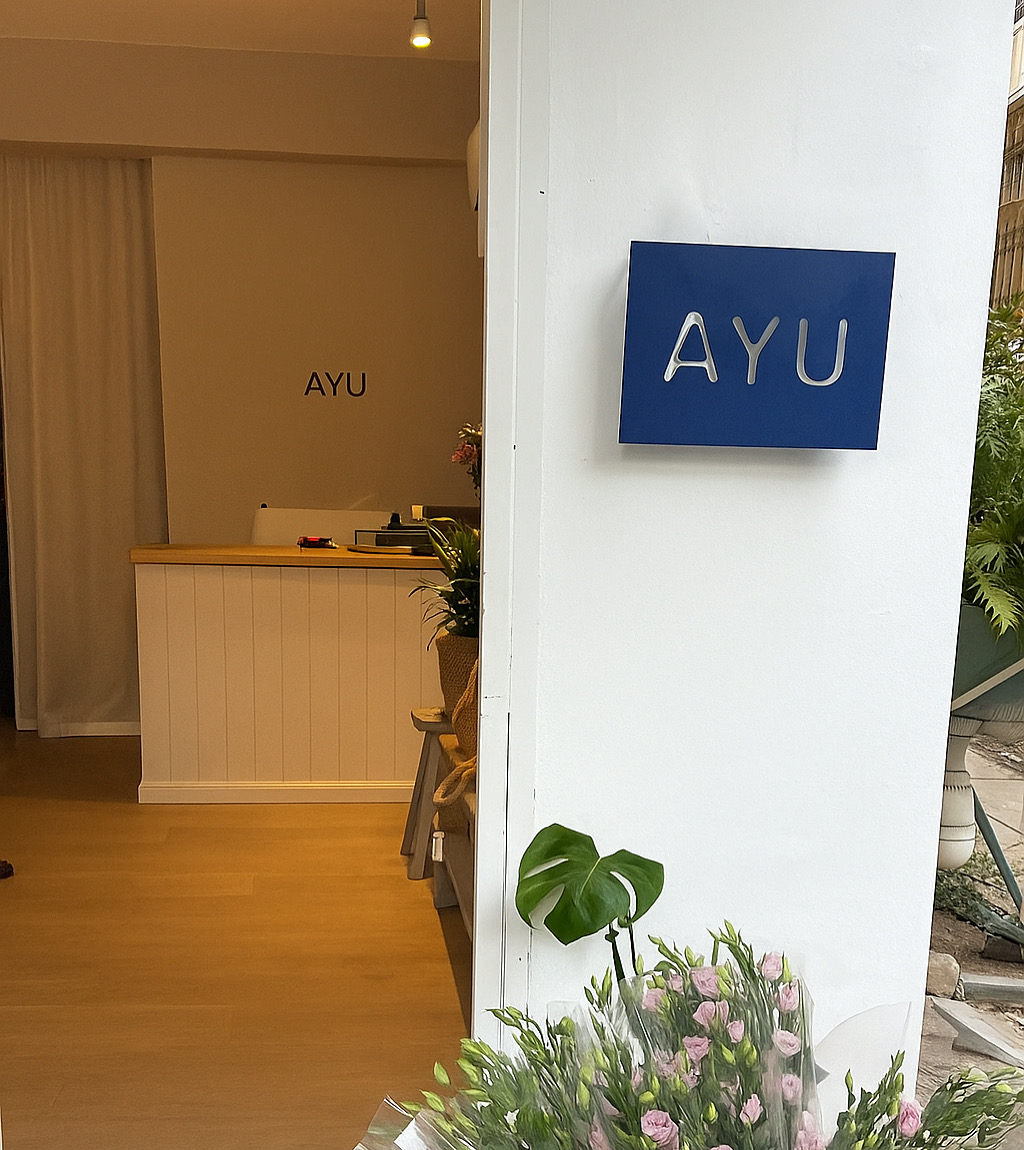 שלט AYU כחול ממתכת על קיר בכניסה לעסק
