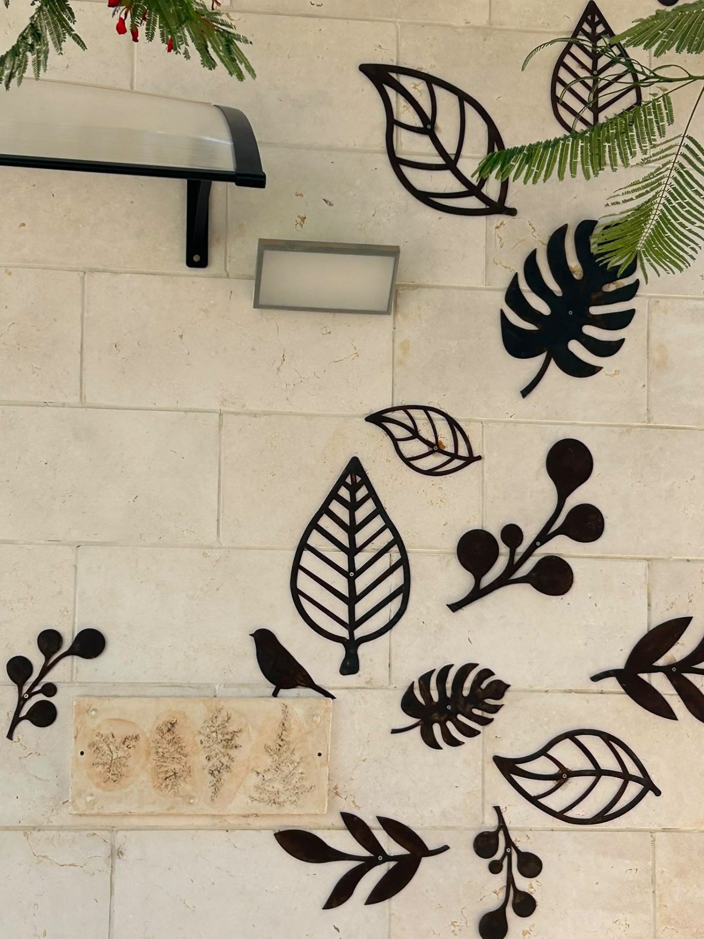 קיר אבן עם עלי מתכת וציפור ממתכת